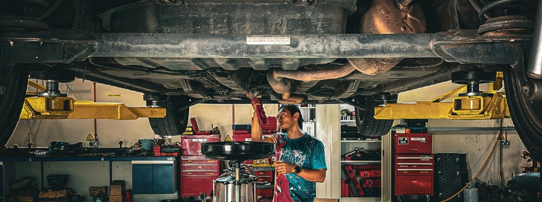 A stock photo of a person draining fluids from a car.